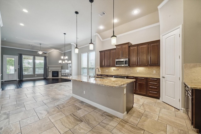 kitchen featuring stainless steel microwave, ornamental molding, decorative backsplash, and a sink