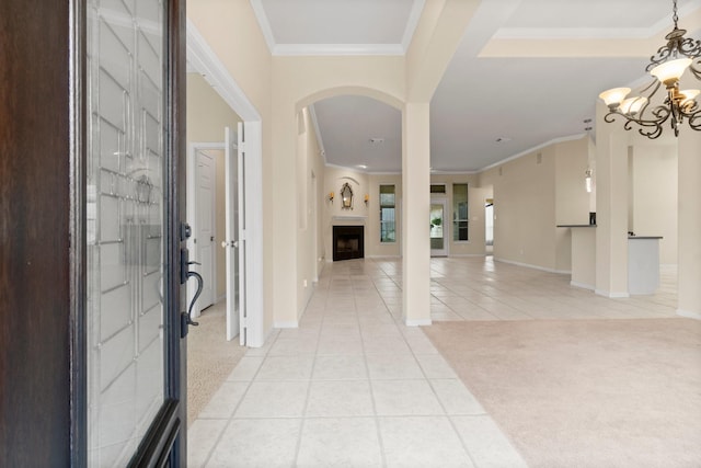 entrance foyer featuring light tile patterned floors, a fireplace, crown molding, light colored carpet, and a chandelier