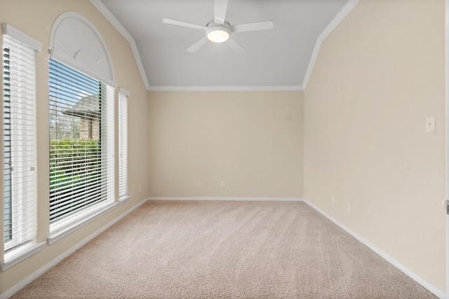 carpeted spare room featuring vaulted ceiling, a ceiling fan, baseboards, and ornamental molding