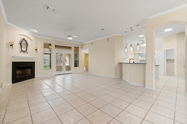 unfurnished living room with visible vents, crown molding, a fireplace, light tile patterned flooring, and a ceiling fan