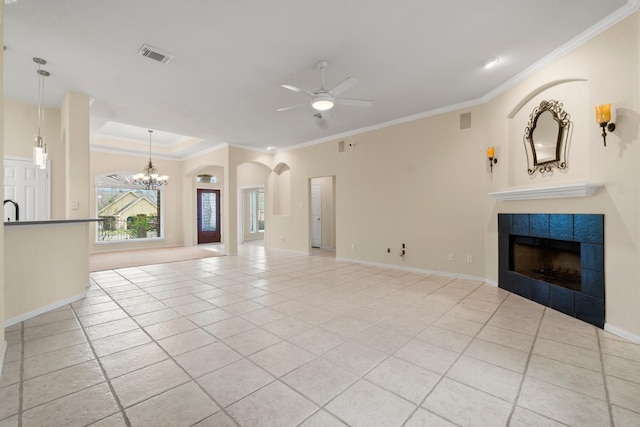 unfurnished living room featuring visible vents, ceiling fan with notable chandelier, light tile patterned flooring, crown molding, and a tile fireplace