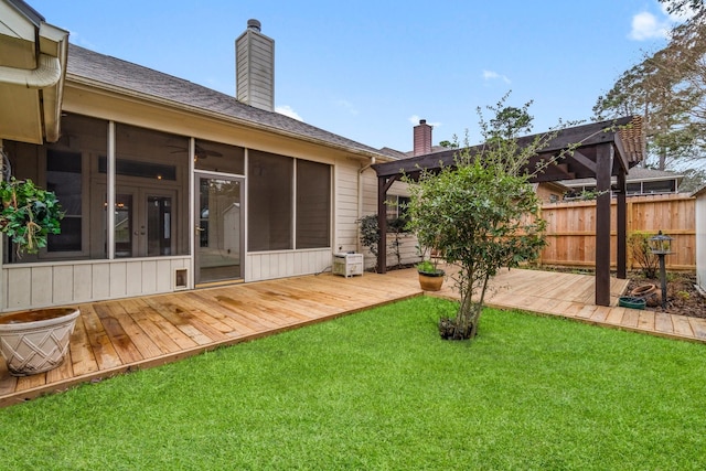 rear view of house featuring fence, a lawn, a sunroom, and a chimney