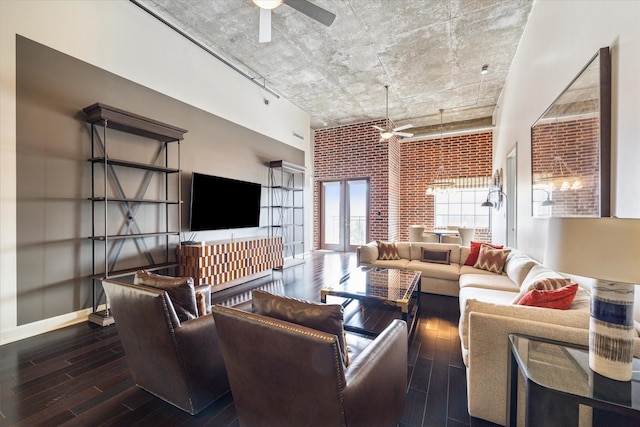living room with wood-type flooring, ceiling fan, a high ceiling, and brick wall