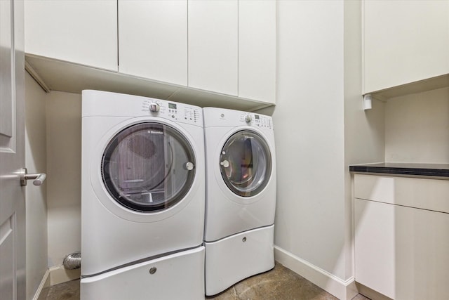 washroom featuring baseboards, cabinet space, and independent washer and dryer