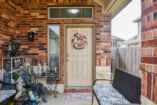 doorway to property with brick siding and fence