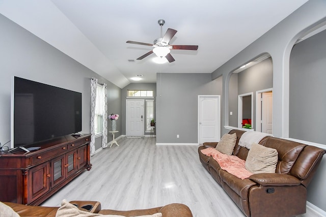 living area featuring ceiling fan, baseboards, vaulted ceiling, light wood-style floors, and arched walkways