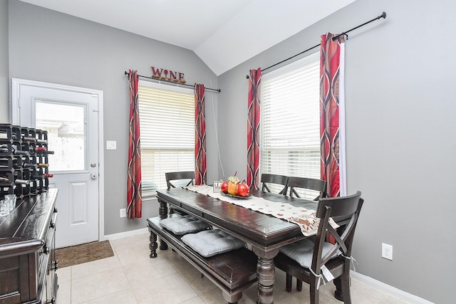 dining area featuring light tile patterned floors, baseboards, and vaulted ceiling