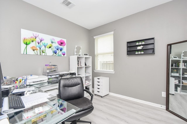 office area with light wood finished floors, visible vents, and baseboards