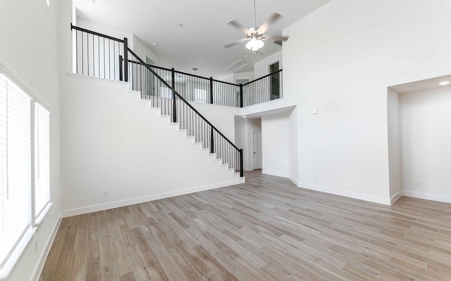 409 Twin Lakes Blvd, West Columbia, TX 77486 - unfurnished living room featuring healthy amount of natural light, stairway, a ceiling fan, a high ceiling, and light wood-style floors