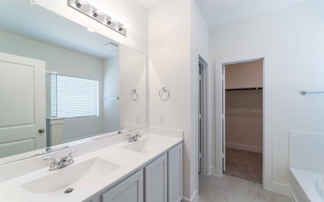 409 Twin Lakes Blvd, West Columbia, TX 77486 - bathroom with double vanity, a bath, a walk in closet, baseboards, and marble look tiles