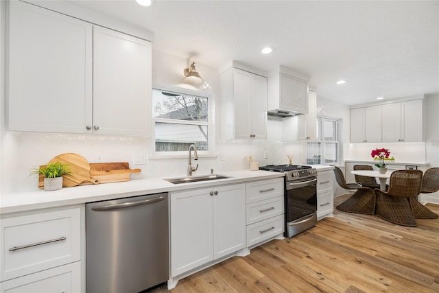 kitchen with light wood-style flooring, a sink, appliances with stainless steel finishes, white cabinetry, and a wealth of natural light