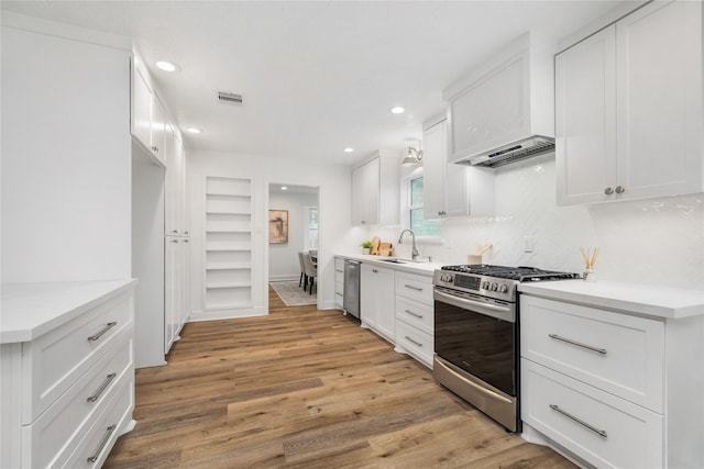 kitchen with visible vents, decorative backsplash, light wood-style flooring, appliances with stainless steel finishes, and white cabinetry