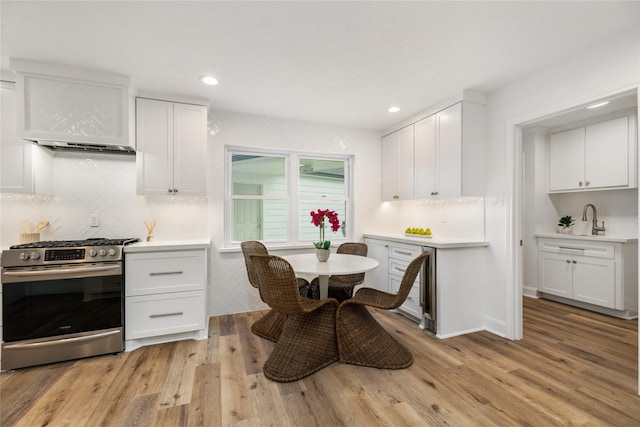 kitchen featuring light wood finished floors, gas range, light countertops, and white cabinetry