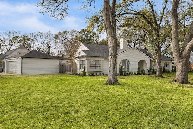 exterior space featuring fence, a chimney, a front lawn, a detached garage, and brick siding