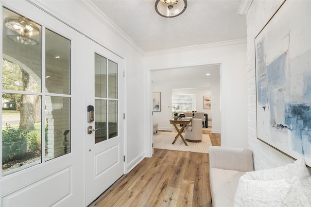 entryway with crown molding, light wood-style floors, baseboards, and a textured ceiling