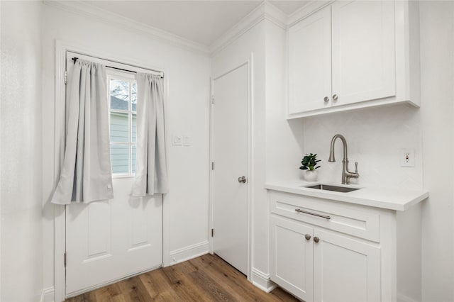 interior space featuring dark wood-type flooring, ornamental molding, baseboards, and a sink