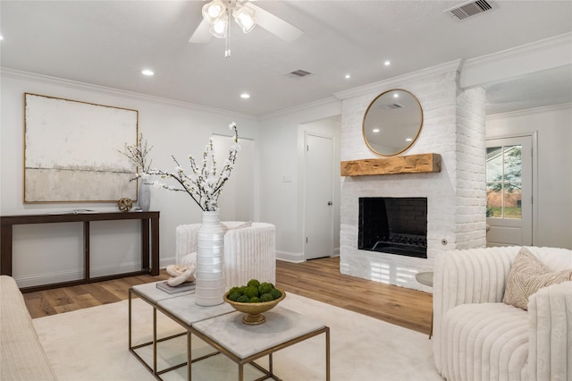 living area with visible vents, ornamental molding, and wood finished floors