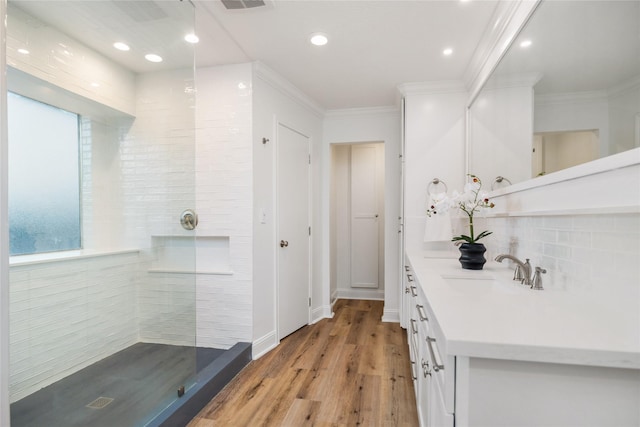 full bathroom featuring wood finished floors, crown molding, decorative backsplash, walk in shower, and vanity