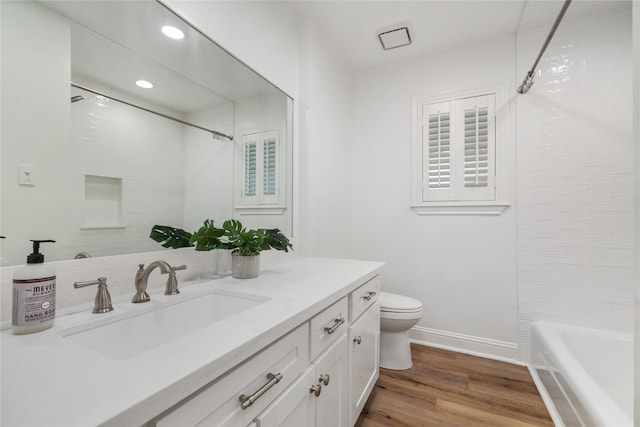 bathroom with baseboards, toilet, recessed lighting, wood finished floors, and vanity