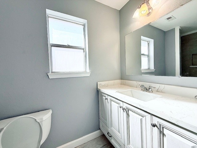 bathroom featuring vanity, toilet, baseboards, and visible vents