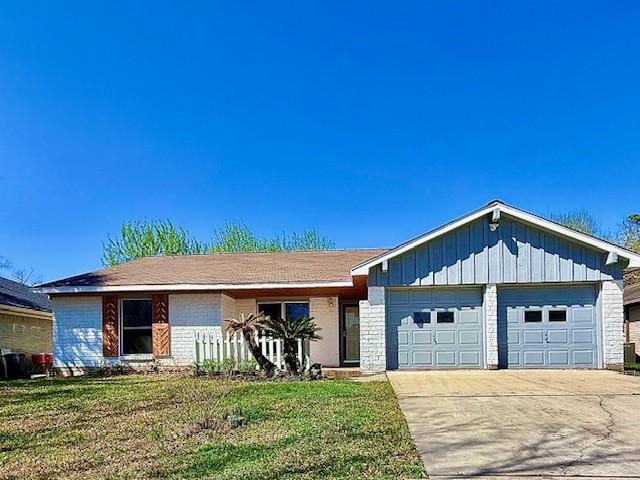 ranch-style house with board and batten siding, concrete driveway, a front yard, a garage, and brick siding