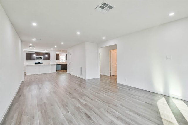 unfurnished living room with visible vents, baseboards, recessed lighting, light wood-style floors, and a sink