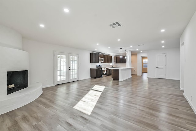 unfurnished living room featuring visible vents, light wood-style flooring, recessed lighting, french doors, and baseboards