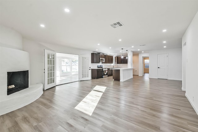 unfurnished living room featuring visible vents, recessed lighting, light wood-type flooring, and baseboards