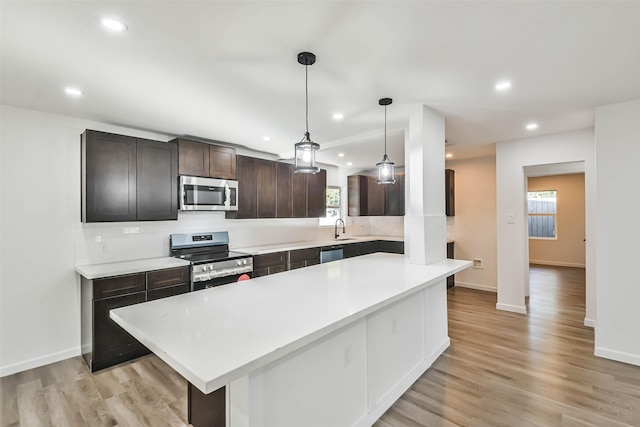 kitchen featuring light wood-style flooring, stainless steel appliances, light countertops, and a sink