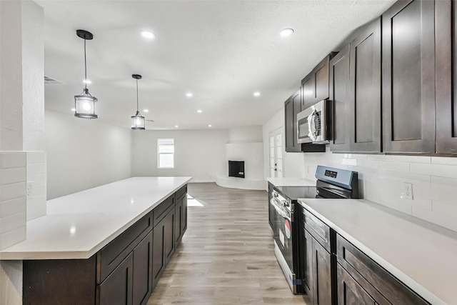 kitchen featuring dark brown cabinetry, stainless steel appliances, light countertops, and light wood-style floors