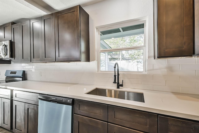 kitchen with decorative backsplash, stainless steel appliances, light countertops, and a sink