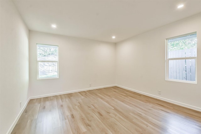 empty room featuring light wood finished floors, recessed lighting, and baseboards