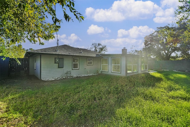 back of house featuring a yard, a fenced backyard, and a chimney