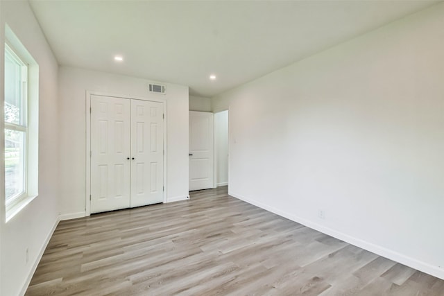 unfurnished bedroom featuring light wood finished floors, visible vents, and baseboards