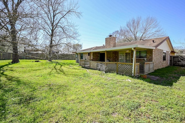 back of property featuring a yard, brick siding, a fenced backyard, and a chimney