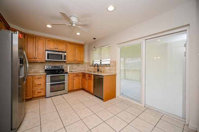 kitchen with a sink, decorative backsplash, ceiling fan, and stainless steel appliances