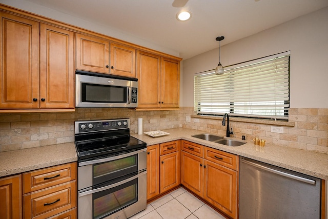 kitchen featuring light tile patterned flooring, brown cabinetry, appliances with stainless steel finishes, and a sink