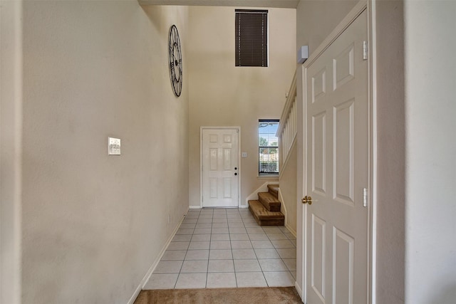 entryway featuring visible vents, baseboards, stairs, light tile patterned floors, and a high ceiling