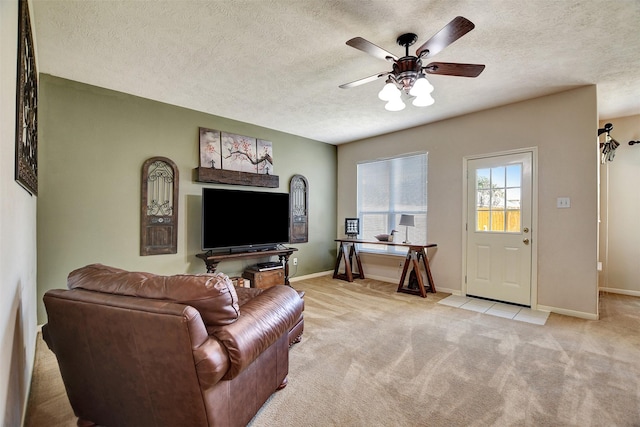 living room featuring baseboards, light carpet, a textured ceiling, and a ceiling fan