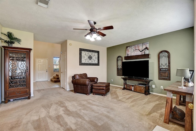 living room with stairway, carpet, visible vents, ceiling fan, and a textured ceiling