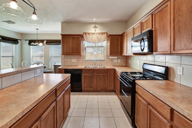 kitchen with visible vents, backsplash, brown cabinetry, black appliances, and a sink