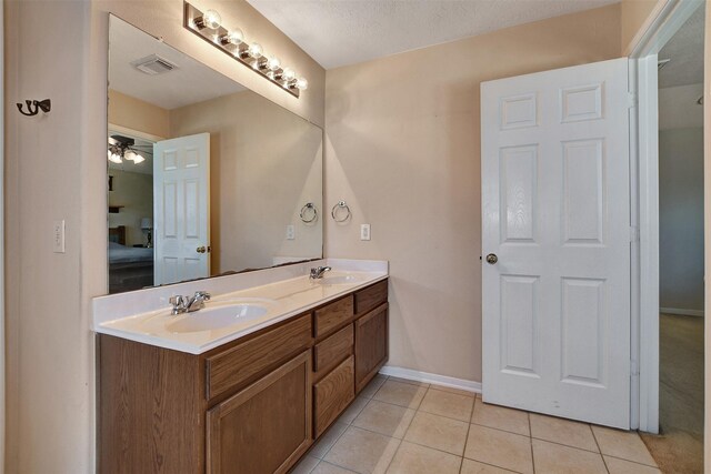 ensuite bathroom with visible vents, double vanity, a sink, ensuite bathroom, and tile patterned floors