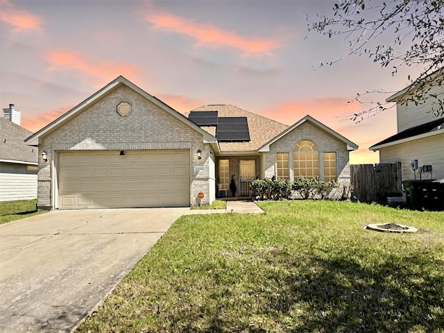 view of front of house featuring concrete driveway, fence, brick siding, and roof mounted solar panels