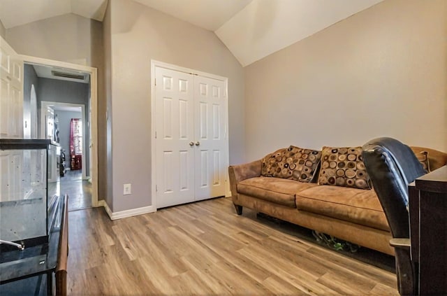 living room with vaulted ceiling, light wood-style floors, and baseboards