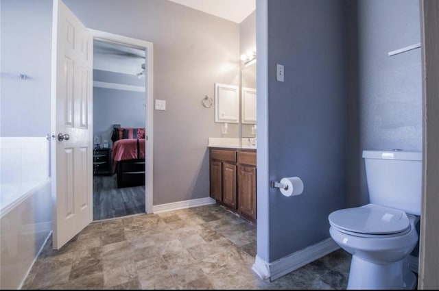 full bathroom featuring baseboards, toilet, vanity, a bath, and ensuite bath