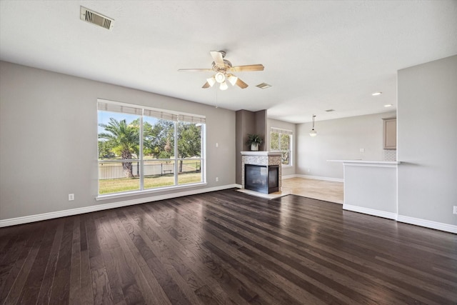 unfurnished living room featuring visible vents, baseboards, a fireplace with flush hearth, and wood finished floors