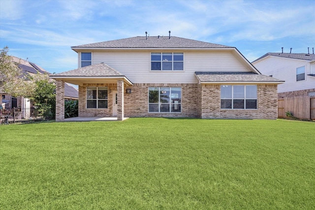 back of property featuring a yard, a patio, brick siding, and a fenced backyard