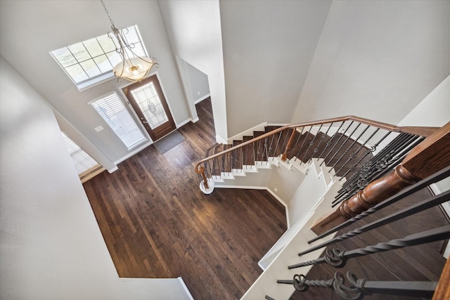 foyer entrance with stairway, wood finished floors, baseboards, and a towering ceiling