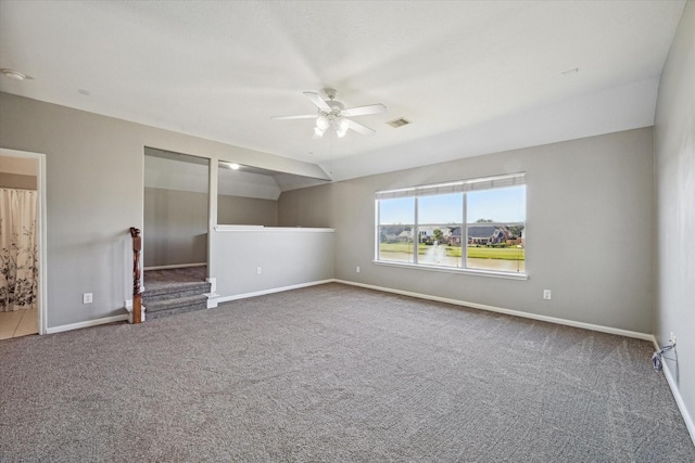 carpeted empty room featuring visible vents, baseboards, lofted ceiling, and a ceiling fan