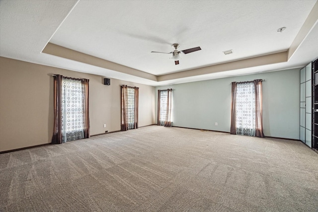 spare room with a raised ceiling, visible vents, and baseboards